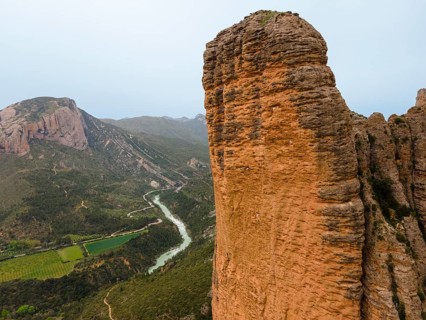 View of a huge rock, a valley with a river below and an impressive natural backdrop, aerial view,