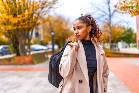 Elegant african american young businesswoman wearing trench coat carrying hand bag in the city in