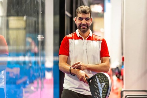 Smiling mature man playing with paddle tennis racket in an indoor court