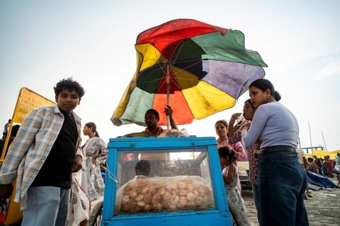 GUWAHATI, INDIA - APRIL 5: A vendor sells panipuri as he stand under a large umbrella during a pre