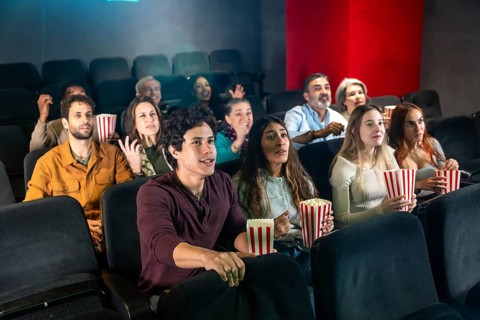 People are watching a movie and eating popcorn in a movie theater, enjoying the show together