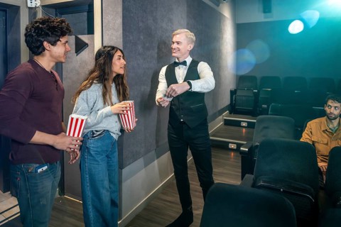 Couple holding popcorn buckets giving their tickets to the usher before entering the movie theater