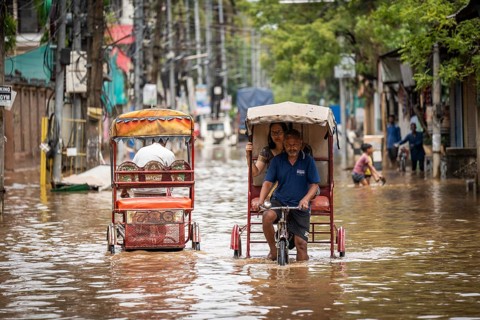 Commuters in cycle rickshaws as they wade through a flooded street after heavy rains in Guwahati,