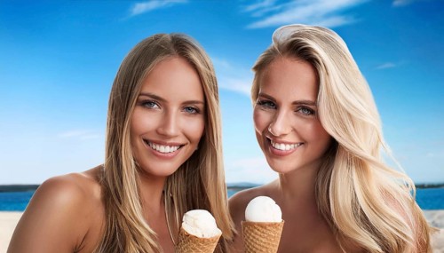Two blonde woman enjoy eating an ice cream in a cone