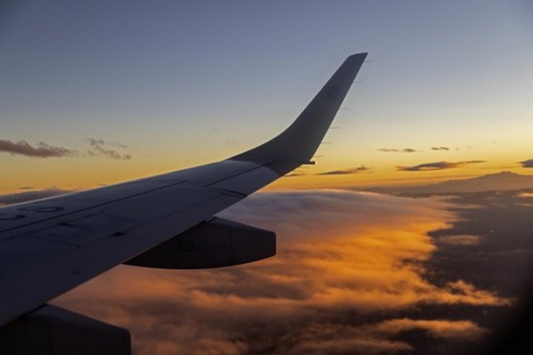 Mexico City, An AeroMexico Connect Embraer jet flies over orange clouds as it approaches Mexico