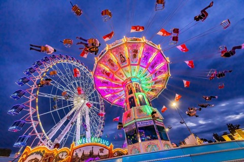 Chain carousel and Ferris wheel in the evening. 177th Cannstatter Volksfest at the Cannstatter