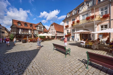Market square with benches, historic buildings and half-timbered houses under a blue sky with