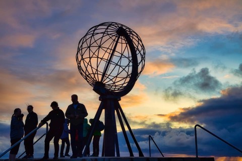 Tourists in front of the steel globe at the North Cape in the evening light, Nordkapp, Finnmark,