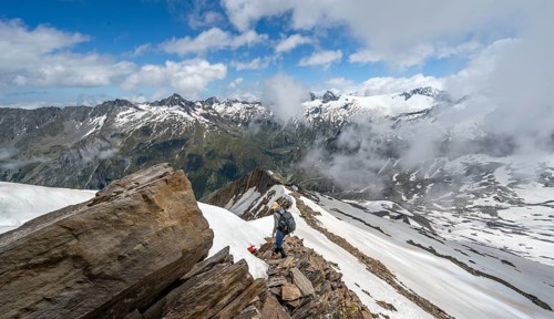 Mountaineer on a rocky ridge with snow, descent from the summit of Schönbichler Horn, view of