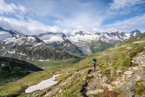 Mountaineer on hiking trail in picturesque mountain landscape, mountain peak with snow and glacier