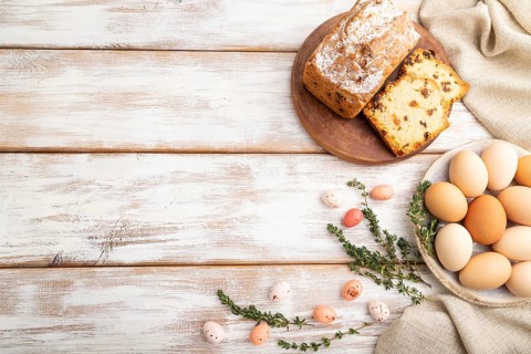 Homemade easter pie with raisins and eggs on plate on a gray concrete background and linen textile.