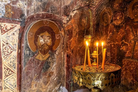 Candlelit orthodox wall painting in a dark, mystical setting, icon depicting Christ, church of Agia
