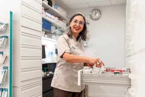 Side view photo of a woman cheerful pharmacist smiling while working in the storage room