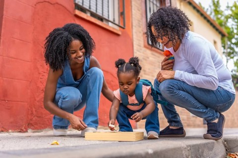 Multi-generation african woman playing with girl and toys in the street