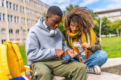 Students addicted to technology and the internet sitting outside the campus using digital tablet