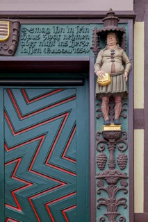 Detailed wooden door of a half-timbered house with statue and decorated façade, clear zigzag