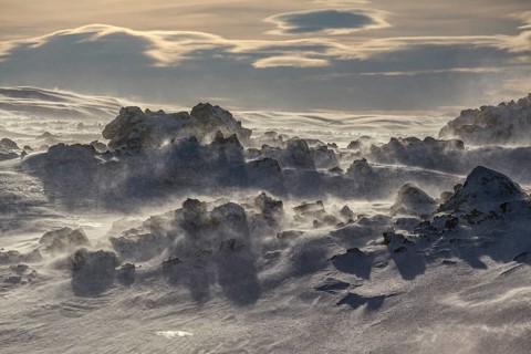 Solidified lava and stones in a snowstorm, windy, sunny, backlight, Myvatn, Iceland, Europe