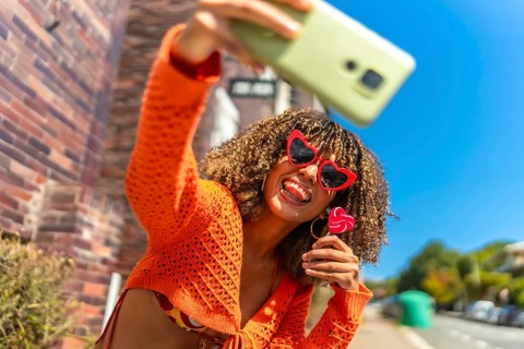 Young and vital latin woman taking selfie while eating lollipop outdoors
