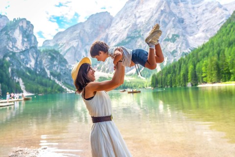 Happy mother lifting her son, enjoying summer vacation at lake braies - pragser wildsee - in the