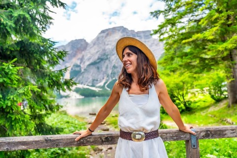 Woman wearing straw hat enjoying the landscape at lake braies, also called pragser wildsee, during