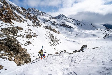 Mountaineer with skis climbing up a steep snow slope to the fork Porta d'Es-cha, ski tour Bündner