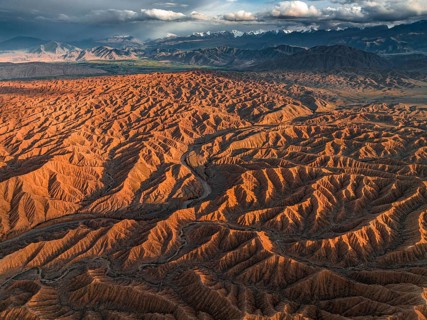 Landscape of eroded hills, badlands at sunset, mountain peaks of the Tian Shan Mountains in the