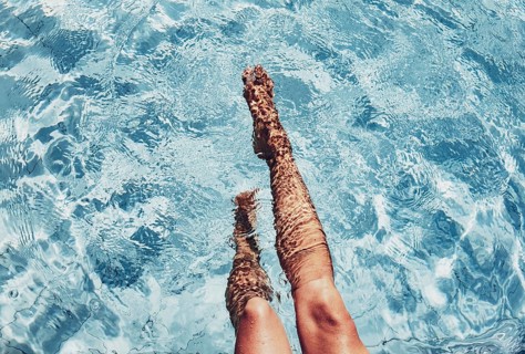Two legs protrude from the blue pool water, calming beauty