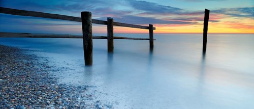 Sunset at Darßer Ort, fence and posts on the Baltic Sea as the border of the cordoned-off core zone