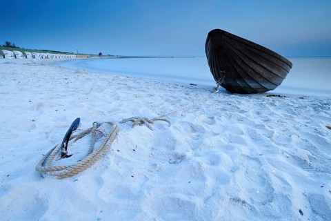 Small wooden boat anchored on the beach of the Baltic Sea, Weststrand Darß, long exposure after