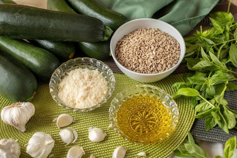 Courgettes, sunflower seeds, cheese, olive oil, garlic and basil on a table