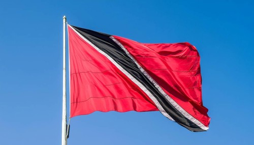 The flag of Tobago, Caribbean, flutters in the wind, isolated against a blue sky