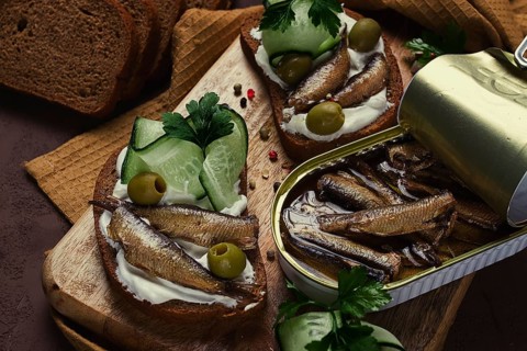 Sandwiches, black bread with sprats, cream cheese, cucumbers, on a cutting board, top view,