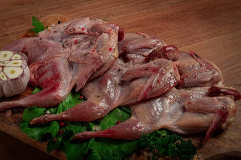 Raw quail meat, on a cutting board, with spices and herbs, top view