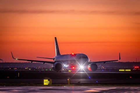 Early in the morning in front of sunrise at the airport, a Lufthansa aircraft stands ready for