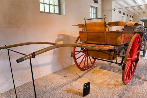 Historic wooden carriage with red wheels in a museum exhibition room, Tonneau carriage of the