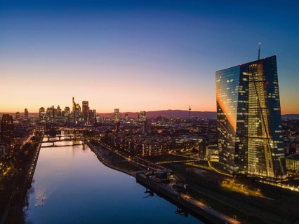 The lights in the offices of the European Central Bank (ECB) and the Frankfurt skyline glow in the