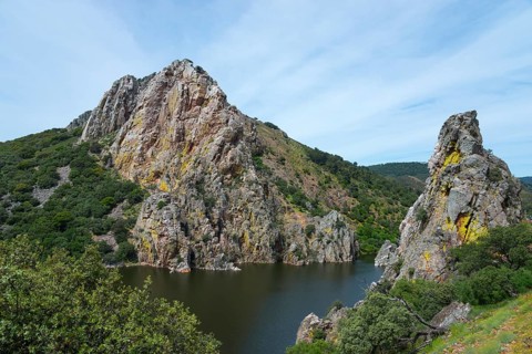 Large rock formations on the banks of a river under a blue sky, Salto del Gitano, River Tagus,
