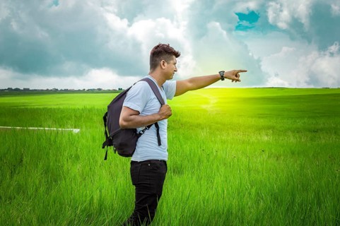 Adventurous man in the field, man with backpack in the field looking