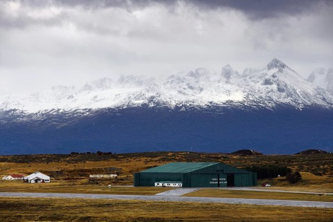 View from the deck of the cruise ship to an industrial hall in front of a snow-covered mountain