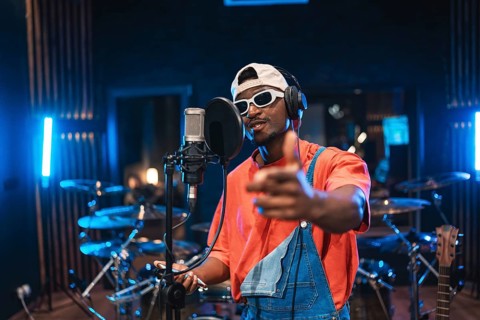 Talented musician recording vocals, pointing at you, wearing trendy sunglasses and cap, creating