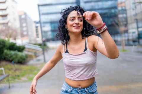Carefree young latin woman enjoying dancing outdoors in urban environment, expressing joy and