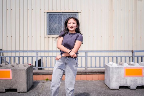 Happy vital young asian woman gesturing while dancing k-pop choreography in the city