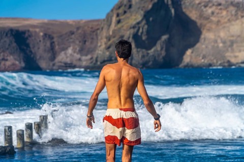 Tourist admiring the ocean waves in the natural pools of agaete, a charming coastal town in gran
