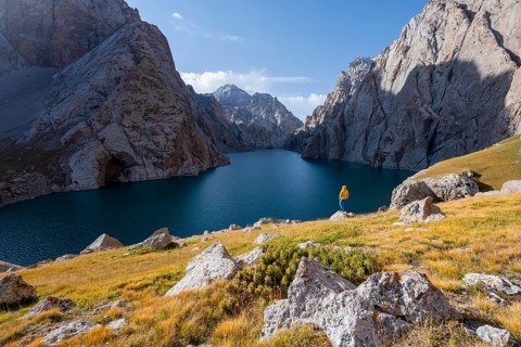 Tourist at the blue mountain lake between rocky steep mountain peaks, Kol Suu Lake, Sary Beles