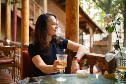 Cheerful and relaxed woman drinking white wine at rustic outdoor cafe enjoying tranquil ambiance of