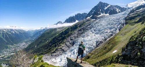 Mountaineer standing on a rock, mountain landscape with glacier Glacier des Bossons and summit of