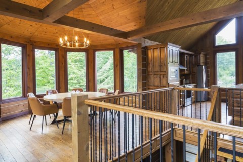 Staircase, round wooden dining table with tan leather armchairs in dining room, plus kitchen inside