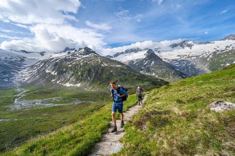 Two mountaineers on hiking trail in picturesque mountain landscape, mountain peak with snow and