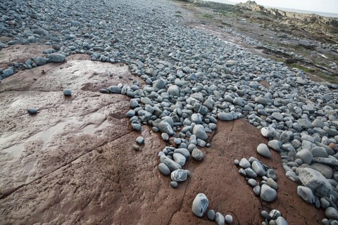 Attrition and abrasion on the wave cut platform as pebbles are rounded and transported, Watchet,