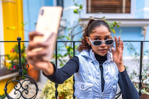 Beauty african american woman millennial in urban clothes taking selfie outside a colorful house
